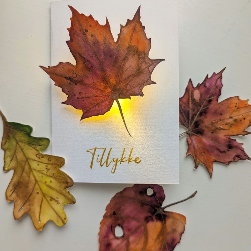 Et efterårsblad i varmt lys – malet med Karin Brushmarkers Pro og gjort til et akvarelkort med LED-lys.